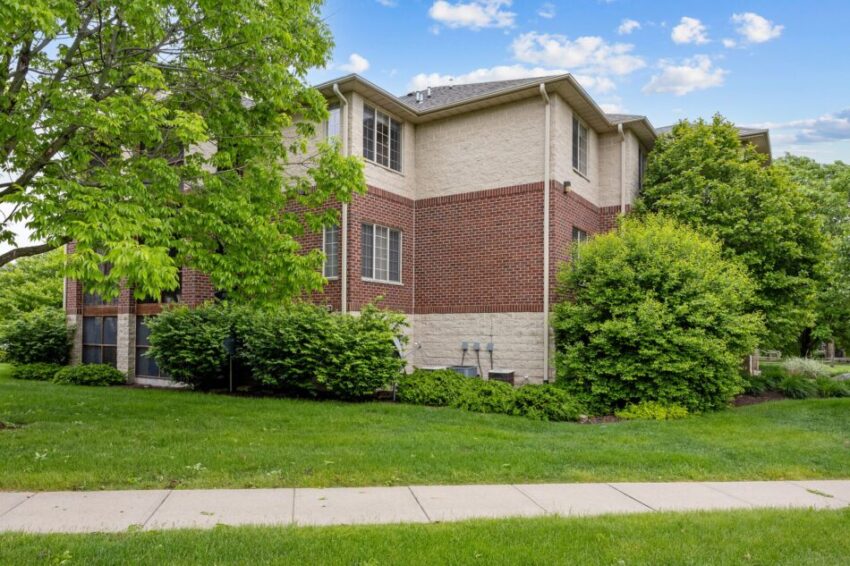 Two-story brick building surrounded by green trees and grass.