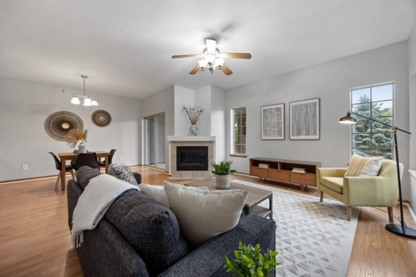 Modern living room with fireplace, sofa, dining area, and large windows.