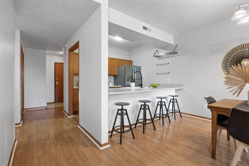 Modern kitchen with bar stools, wooden flooring, and dining area.