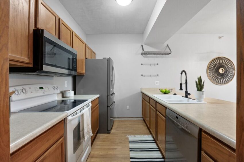 Modern kitchen with wooden cabinets, stainless steel appliances, and a decorative wall piece.