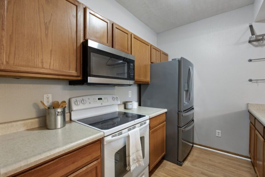 Modern kitchen with wooden cabinets, stainless steel appliances, and light countertops.