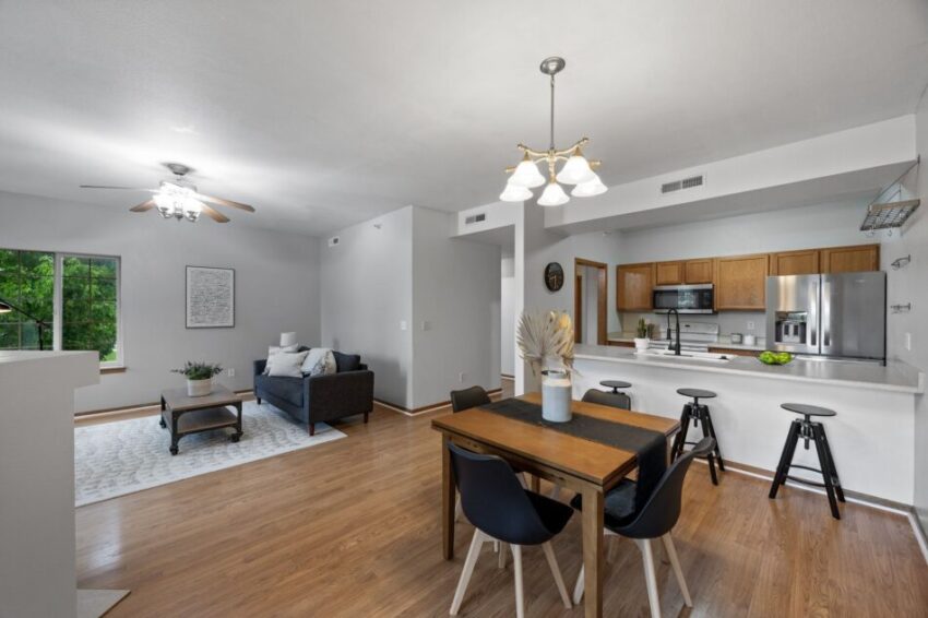 Open-concept living room and kitchen with modern furniture and wooden flooring.