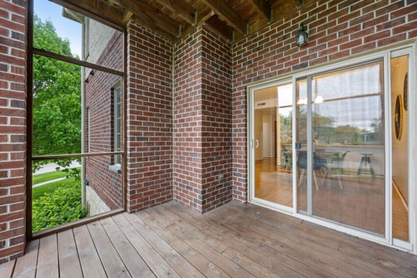 Brick patio with wooden floor and sliding glass doors.