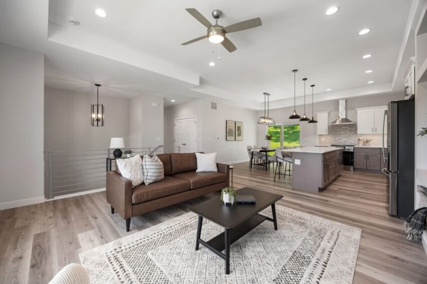 Modern open-concept living room and kitchen with neutral tones and ceiling fans.