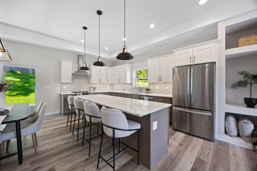 Modern kitchen with island, pendant lights, and two-toned cabinets.