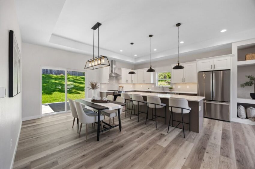 Modern kitchen with island, bar stools, and pendant lights, overlooking a dining area.