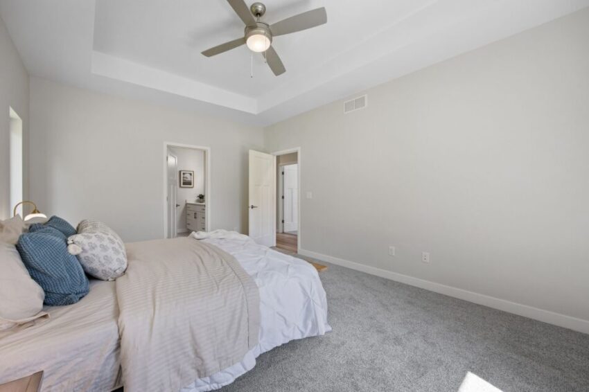 Spacious bedroom with bed, ceiling fan, and open door to bathroom.