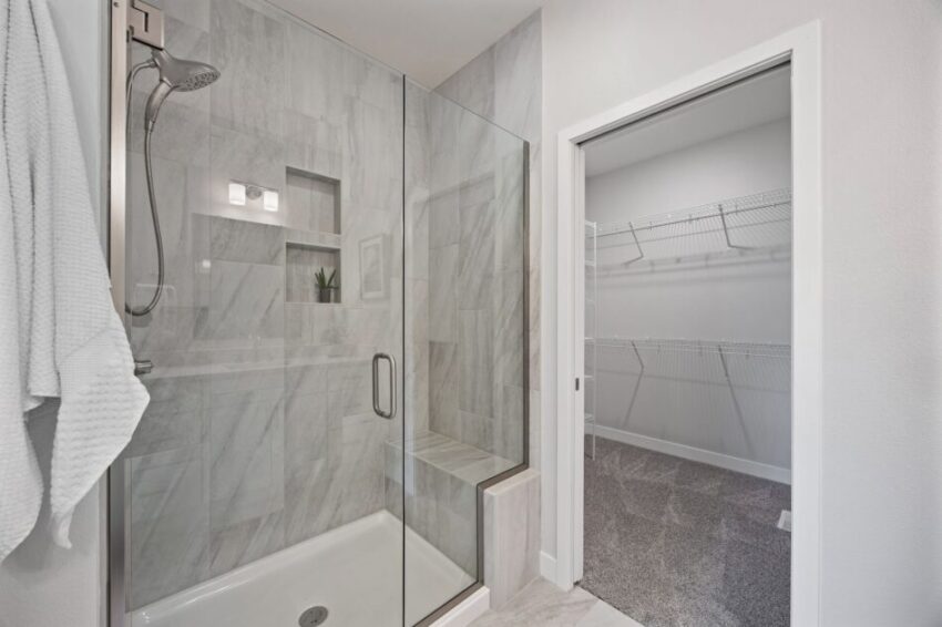 Modern bathroom with glass shower and adjacent walk-in closet.