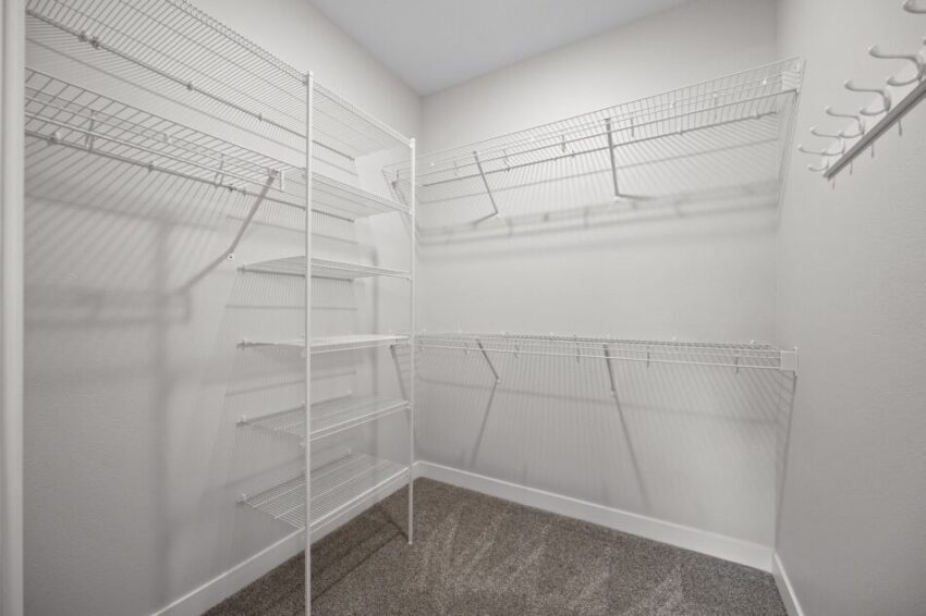Empty walk-in closet with white wire shelving and gray carpet.