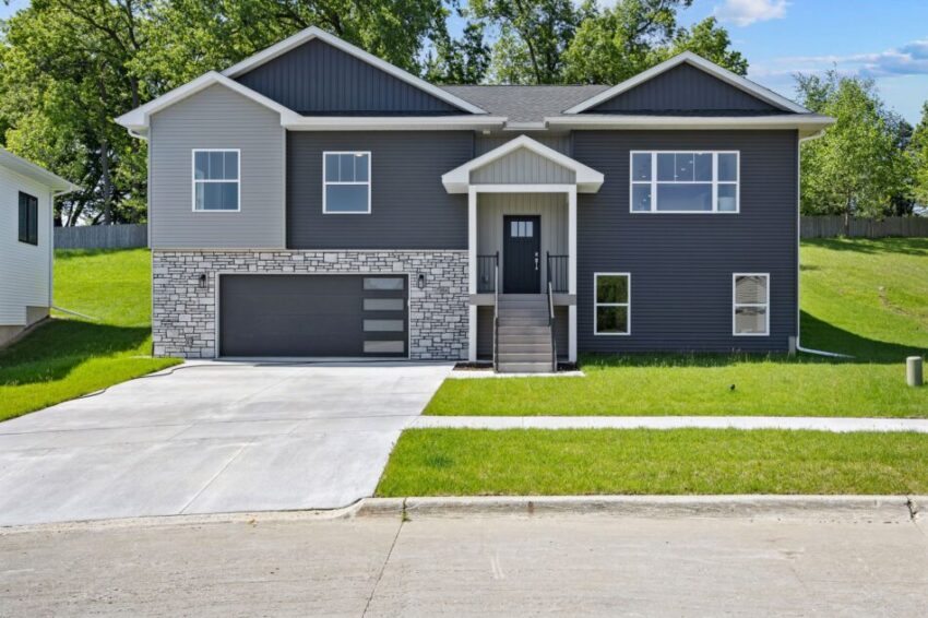 Modern two-story house with gray siding and stone accents, surrounded by green lawn.
