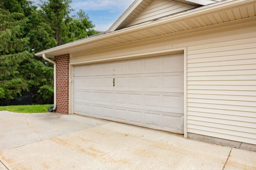 Closed white garage door on a suburban house with brick and siding.
