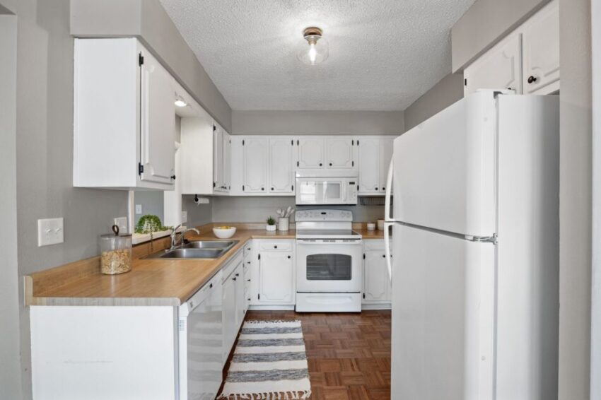 White kitchen with wooden countertops and modern appliances.