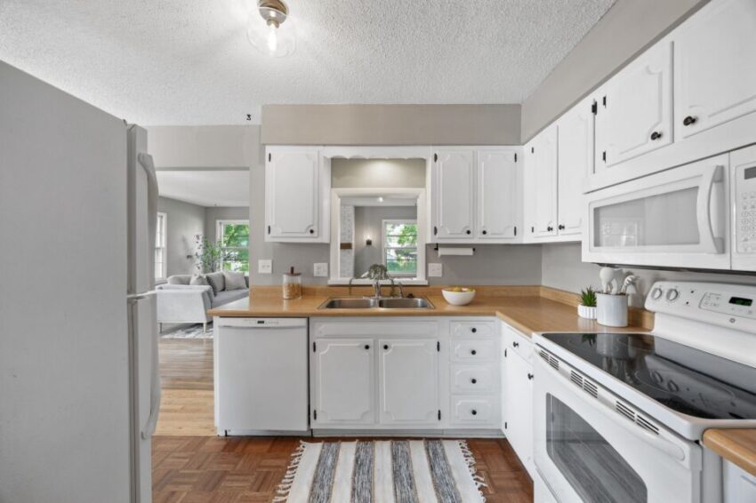 White kitchen with wooden countertops, modern appliances, and a striped rug.