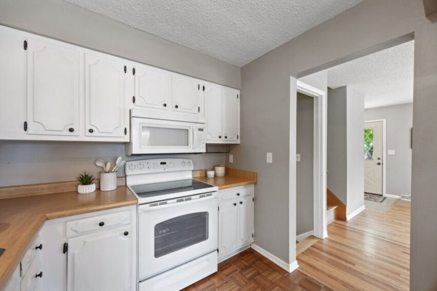 White kitchen with wooden countertops and a white stove.