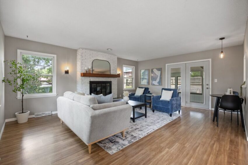 Modern living room with fireplace, sofa, chairs, and large windows.