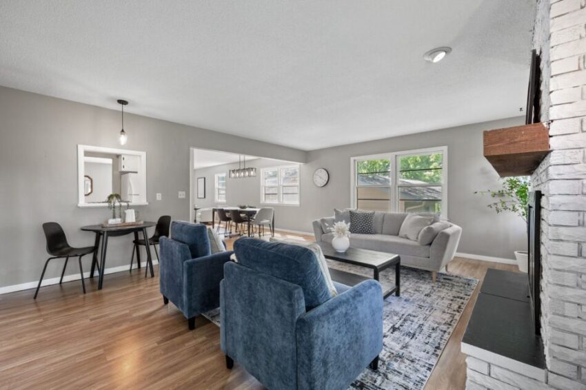 Spacious living room with blue chairs, gray sofa, and wooden floor.