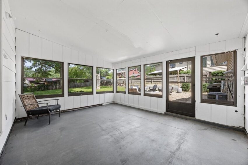 Spacious sunroom with large windows overlooking a backyard garden.