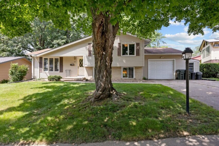 Suburban house with a tree in front yard and attached garage.