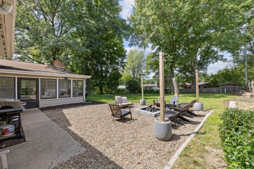 Backyard with patio furniture, fire pit, and surrounding trees.