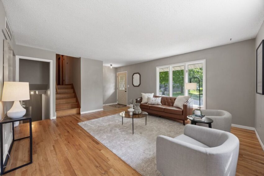 Modern living room with hardwood floors, brown sofa, and large windows.