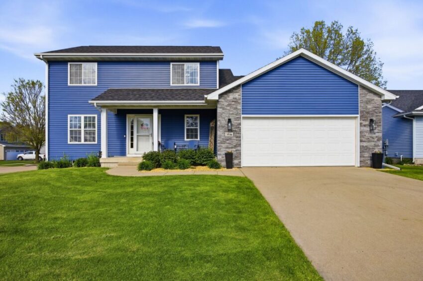 Two-story blue house with white trim, attached garage, and well-maintained front lawn.