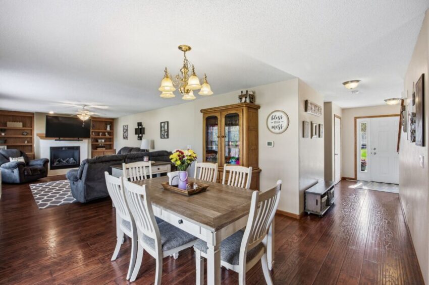 Open living and dining area with wooden floors, white chairs, and natural light.