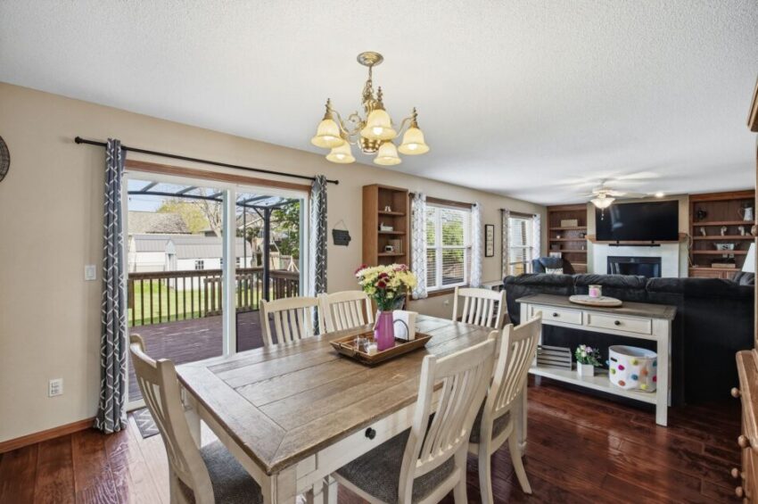 Bright dining area with wooden table, chairs, and view of living room and backyard deck.