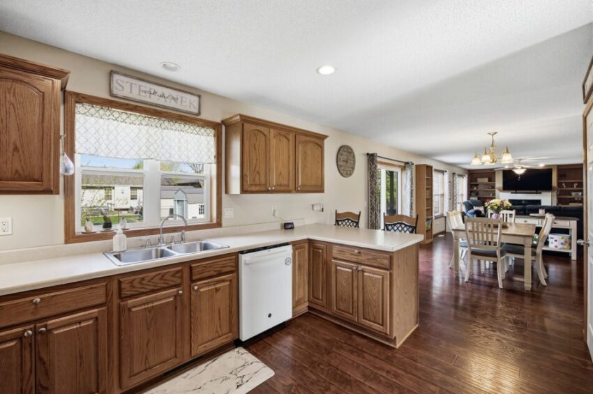 Spacious kitchen with wooden cabinets, white countertops, and dining area overlooking living room.