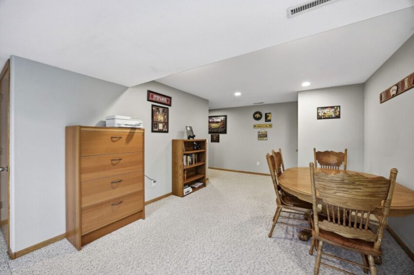 Basement room with wooden dining table, chairs, dresser, bookshelf, and sports-themed wall decor.