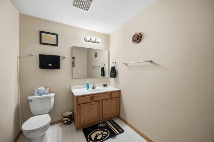 Bathroom with toilet, sink, mirror, towel racks, and Iowa Hawkeyes decor.